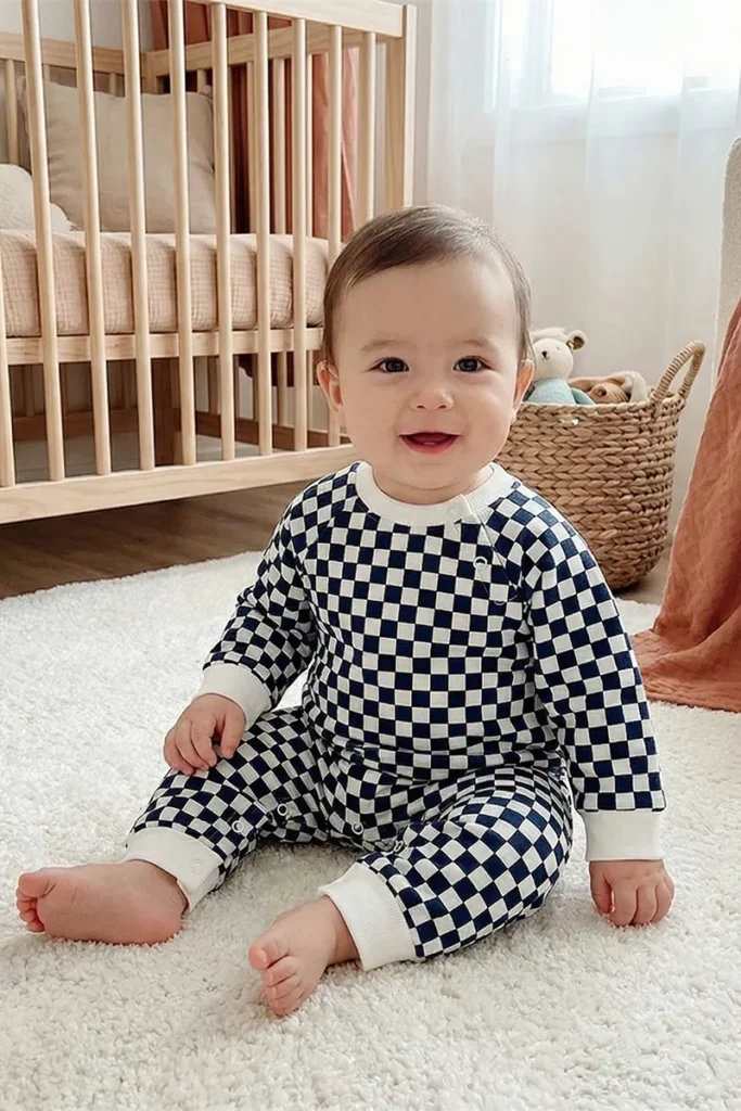 baby long sleeve romper in black and white checkerboard print with white ribbed cuffs.
